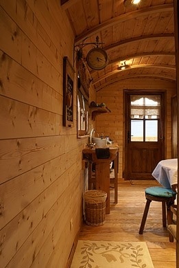 Vue intérieur de la roulotte avec les tabourets en bois et la cuisine .