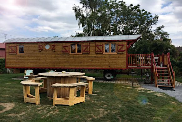 Vue estérieure de la roulotte avec le salon de jardin. 